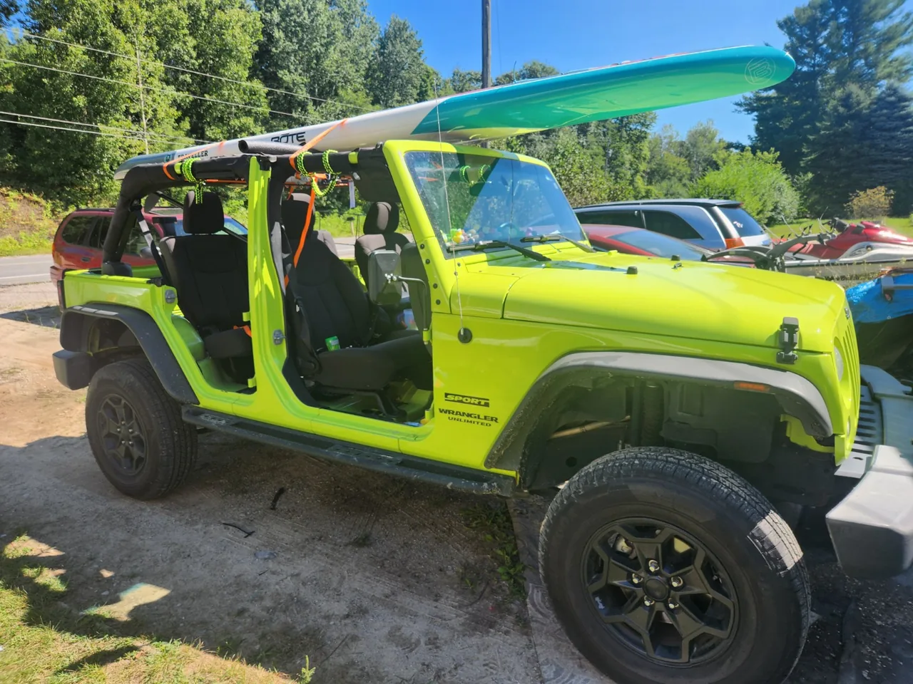 The actual Hyper Green 2017 Jeep Wrangler JK Unlimited with a paddleboard overhead.